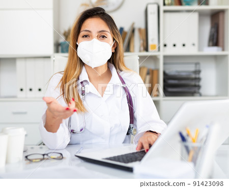 Woman doctor in medical mask is working at laptop 91423098