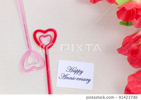 The plastic heart pairs with the happy anniversary card, with many flowers, brown background The plastic heart pairs with the happy anniversary card, with many flowers, brown background 91423786