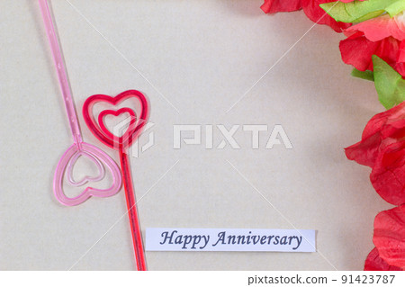 The plastic heart pairs with the happy anniversary card, with many flowers, brown background The plastic heart pairs with the happy anniversary card, with many flowers, brown background 91423787