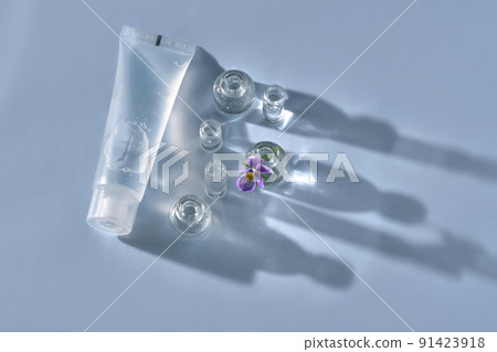 Transparent bottle of cosmetic gel on a blue background with small bottles of water. 91423918