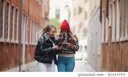 Two young women walking on the narrow streets of Venice and looks the camera Two young women walking on the narrow streets of Venice and looks the camera 91424754