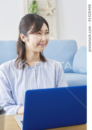 A lady who uses a laptop in the living room A lady who uses a laptop in the living room 91426406