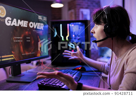 Young player losing video games tournament on computer, feeling sad about lost shooting gameplay competititon. Female gamer playing online rpg action championship on live stream. 91428711