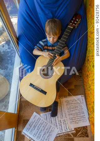 little boy plays guitar and sings on the balcony little boy plays guitar and sings on the balcony 91428756