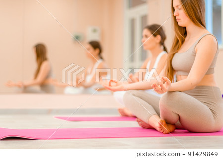 Two young sporty woman, fitness instructor in sportswear doing stretching and pilates on yoga mat in the studio with mirror. Female fitness yoga routine concept. Healthy lifestyle and harmony. 91429849