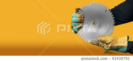 Gloved Hands Holding a Metal Circular Saw Blade Isolated on Orange Background Gloved Hands Holding a Metal Circular Saw Blade Isolated on Orange Background 91430791
