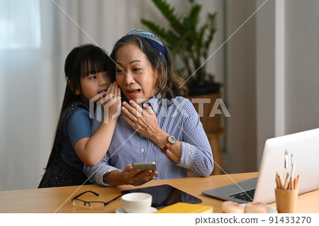 Cute little girl whispering something to senior grandmother. Loving family relationship concept 91433270