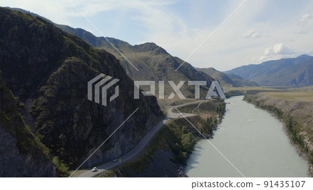 Traffic cars on Chuya highway road between mountains and Katun river under blue sky in Altai Traffic cars on Chuya highway road between mountains and Katun river under blue sky in Altai 91435107