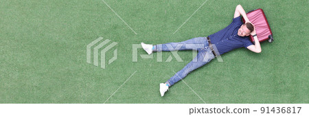 Young man lies on suitcase top view 91436817