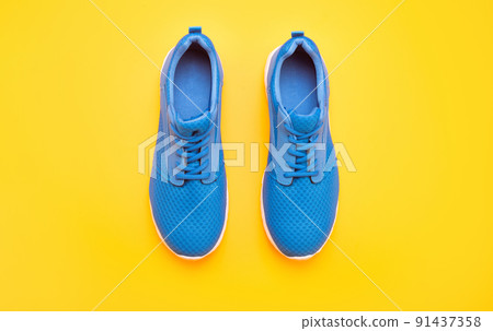 sporty blue sneakers pair on yellow background, footwear sporty blue sneakers pair on yellow background, footwear 91437358