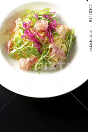 A bird's-eye view of cold pasta using red radish, mizuna, prosciutto, and capellini on a black background 91438506