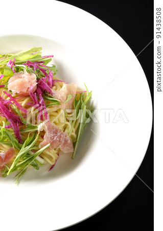 A bird's-eye view of cold pasta using red radish, mizuna, prosciutto, and capellini on a black background 91438508