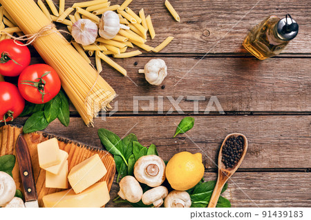 Ingredients for spaghetti with basil, tomatoes, cheese on wooden background, top view, place for text 91439183