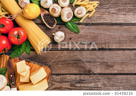 Ingredients for spaghetti with basil, tomatoes, cheese on wooden background, top view, place for text 91439210