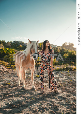 The girl relaxes with the white horse in the nature park 91439726
