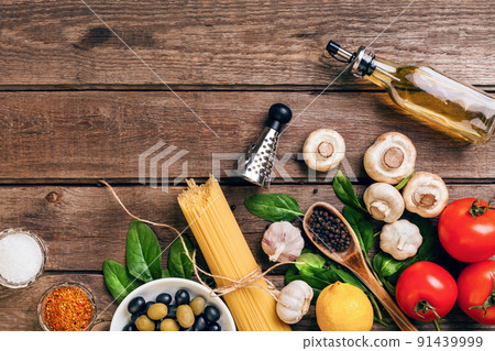 Pasta ingredients - tomatoes, olive oil, garlic, italian herbs, fresh basil, salt and spaghetti on a wooden background with copy space, horizontal, top view 91439999
