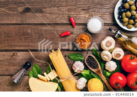 Pasta ingredients - tomatoes, olive oil, garlic, italian herbs, fresh basil, salt and spaghetti on a wooden background with copy space, horizontal, top view 91440014