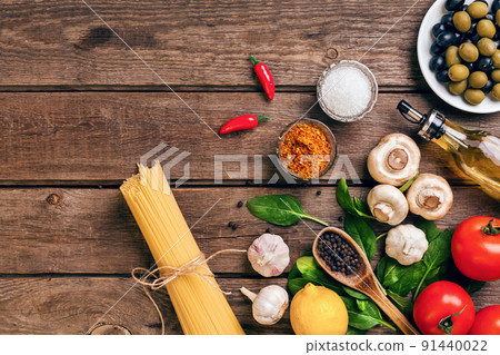 Pasta ingredients - tomatoes, olive oil, garlic, italian herbs, fresh basil, salt and spaghetti on a wooden background with copy space, horizontal, top view 91440022