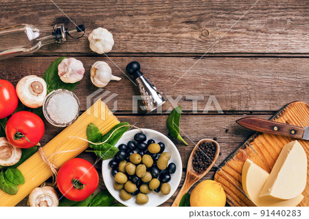 Raw ingredients for the preparation of Italian pasta, spaghetti, basil, tomatoes, olives and olive oil on wooden background. Top view. Copy space. Raw ingredients for the preparation of Italian pasta, spaghetti, basil, tomatoes, olives and olive oil on wooden background. Top view. Copy space. 91440283
