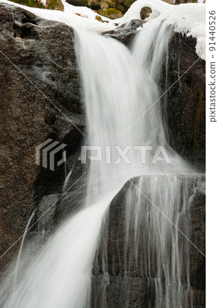 A small active waterfall. Clean mountain stream, snowy winter landscape, wildlife background 91440526