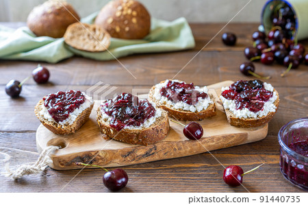 Wholewheat toasts with ricotta and homemade sweet cherry jam 91440735