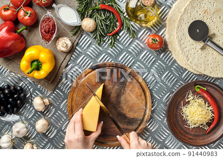 Partial view of woman cutting cheese while cooking homemade italian pizza 91440983