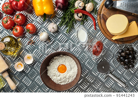 Ingredients and dough for making pizzas with an overhead view on freshly mixed mounds of pastry, a jar of olive oil and pot of tomato sauce, overhead view Ingredients and dough for making pizzas with an overhead view on freshly mixed mounds of pastry, a jar of olive oil and pot of tomato sauce, overhead view 91441243