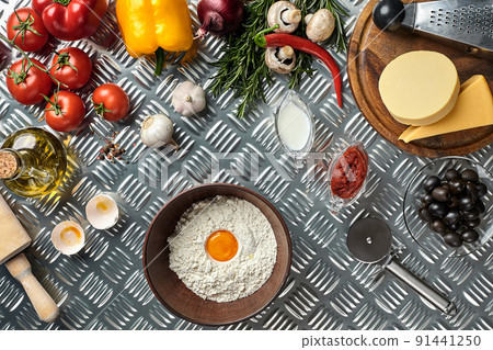Ingredients and dough for making pizzas with an overhead view on freshly mixed mounds of pastry, a jar of olive oil and pot of tomato sauce, overhead view Ingredients and dough for making pizzas with an overhead view on freshly mixed mounds of pastry, a jar of olive oil and pot of tomato sauce, overhead view 91441250
