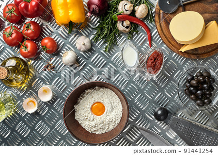 Ingredients and dough for making pizzas with an overhead view on freshly mixed mounds of pastry, a jar of olive oil and pot of tomato sauce, overhead view Ingredients and dough for making pizzas with an overhead view on freshly mixed mounds of pastry, a jar of olive oil and pot of tomato sauce, overhead view 91441254