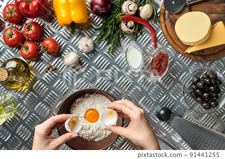 Set of ingredients for pizza and baker's hand smash eggs into bowl on metal table Set of ingredients for pizza and baker's hand smash eggs into bowl on metal table 91441255
