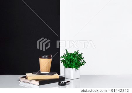 Flowers, book, notebook and cup of coffee, black and white wall. 91442842