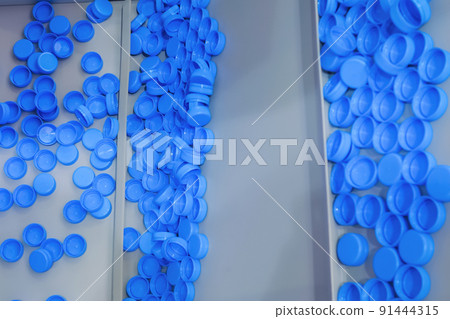 Many blue plastic bottle caps moving on conveyor belt - production line 91444315