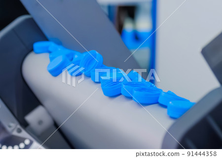 Production line - many blue plastic bottle caps falling from conveyor belt Production line - many blue plastic bottle caps falling from conveyor belt 91444358