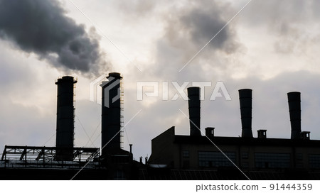 Factory smokestack emitting smoke against sky - environmental pollution Factory smokestack emitting smoke against sky - environmental pollution 91444359