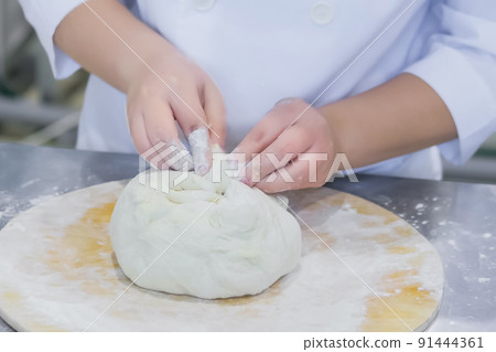 Baker hands kneading fresh dough and making Ossetian pie on table 91444361