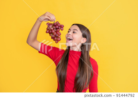 glad amazed kid hold bunch of grapes on yellow background glad amazed kid hold bunch of grapes on yellow background 91444792