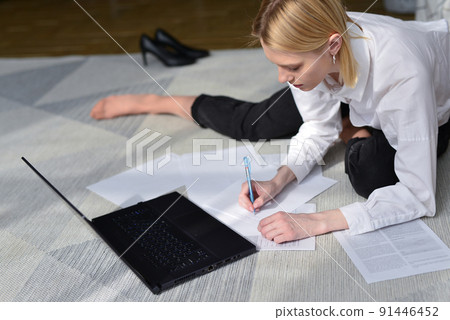 Woman sitting on floor with laptop and documents. 91446452