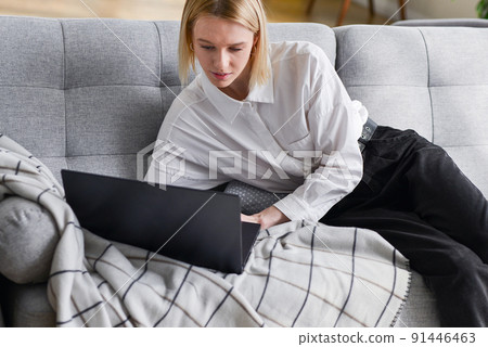 Woman at home lying on couch with laptop Woman at home lying on couch with laptop 91446463