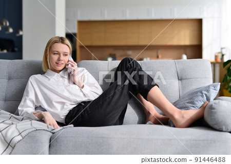 Woman talking on phone lying on couch Woman talking on phone lying on couch 91446488