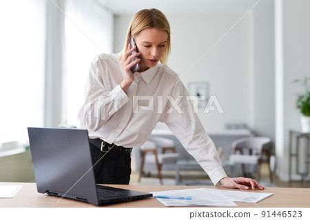 Woman looking at documents and talking on phone 91446523