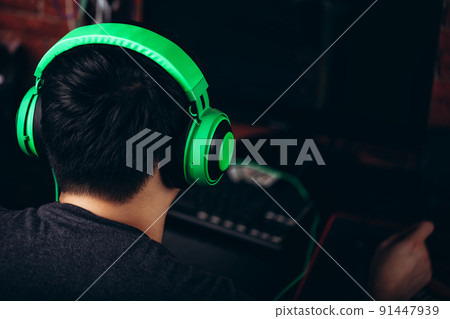 Back view of gamer in headphones playing video game Back view of gamer in headphones playing video game 91447939