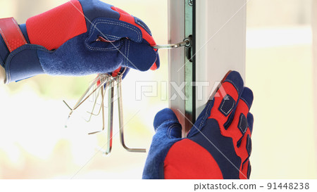Builder repairs plastic window with screwdriver or hexagon indoors closeup Builder repairs plastic window with screwdriver or hexagon indoors closeup 91448238