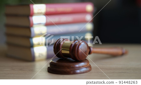 Wooden gavel and stack of books in courtroom 91448263