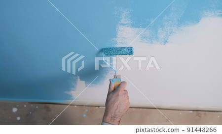Man paints white wall with blue dye closeup Man paints white wall with blue dye closeup 91448266