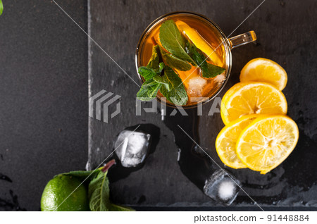 Brewed tea with mint and lemon. Pieces of melting ice and tea. Close-up view of tea from above. Cold tea with mint. 91448884