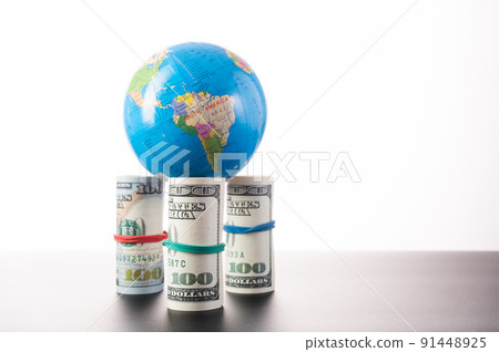 A small globe standing on bundles of money. Globe on money. Globe and money isolate on white background. 91448925