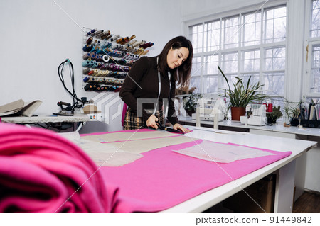 Female fashion designer tailor making sewing patterns at workplace in sewing studio. 91449842