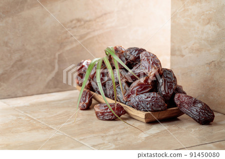 Dates fruit in a wooden dish on a beige ceramic table. Dates fruit in a wooden dish on a beige ceramic table. 91450080