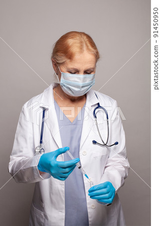 Doctor or nurse holding a syringe with liquid vaccines preparing to do an injection. Doctor or nurse holding a syringe with liquid vaccines preparing to do an injection. 91450950