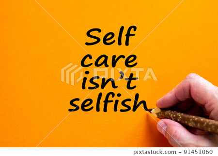 Time to self care. Hand writing 'self care is not selfish', isolated on beautiful orange background. Covid-19 pandemic and medical concept. Copy space. 91451060